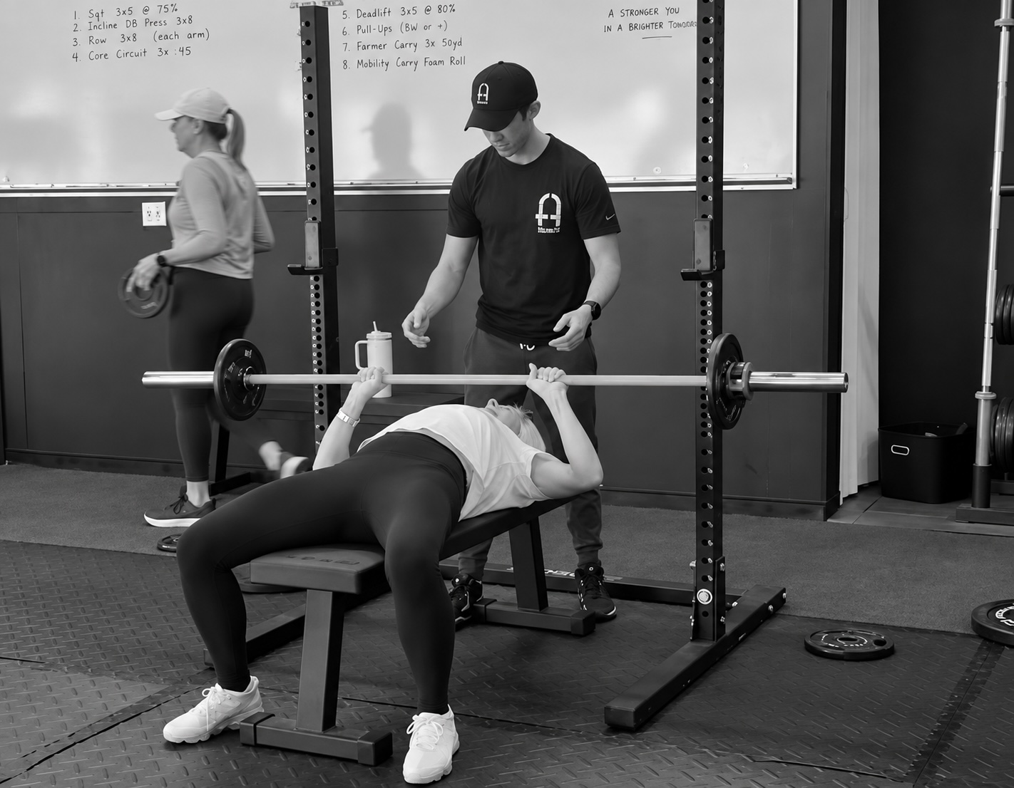 A Fitness Artist coach spotting a member’s bench press